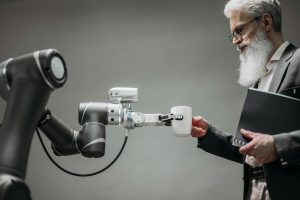 Un robot porge una tazza di te a un uomo. Quale impatto avranno sul mondo del lavoro, e quale stanno già avendo, le nuove tecnologie come l'intelligenza artificiale e l'automazione?