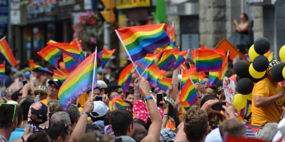 Tanti partecipanti a un pride con le bandierine arcobaleno. Celebrare il Pride ha ancora più senso in un paese come l'Italia e in un periodo storico in cui le destre estreme continuano a mettere in discussione i diritti LGBTQIA+