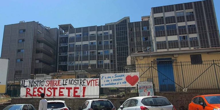 Una foto di Scampia, a Napoli, con dei manifesti in cui si chiede agli abitanti di resistere