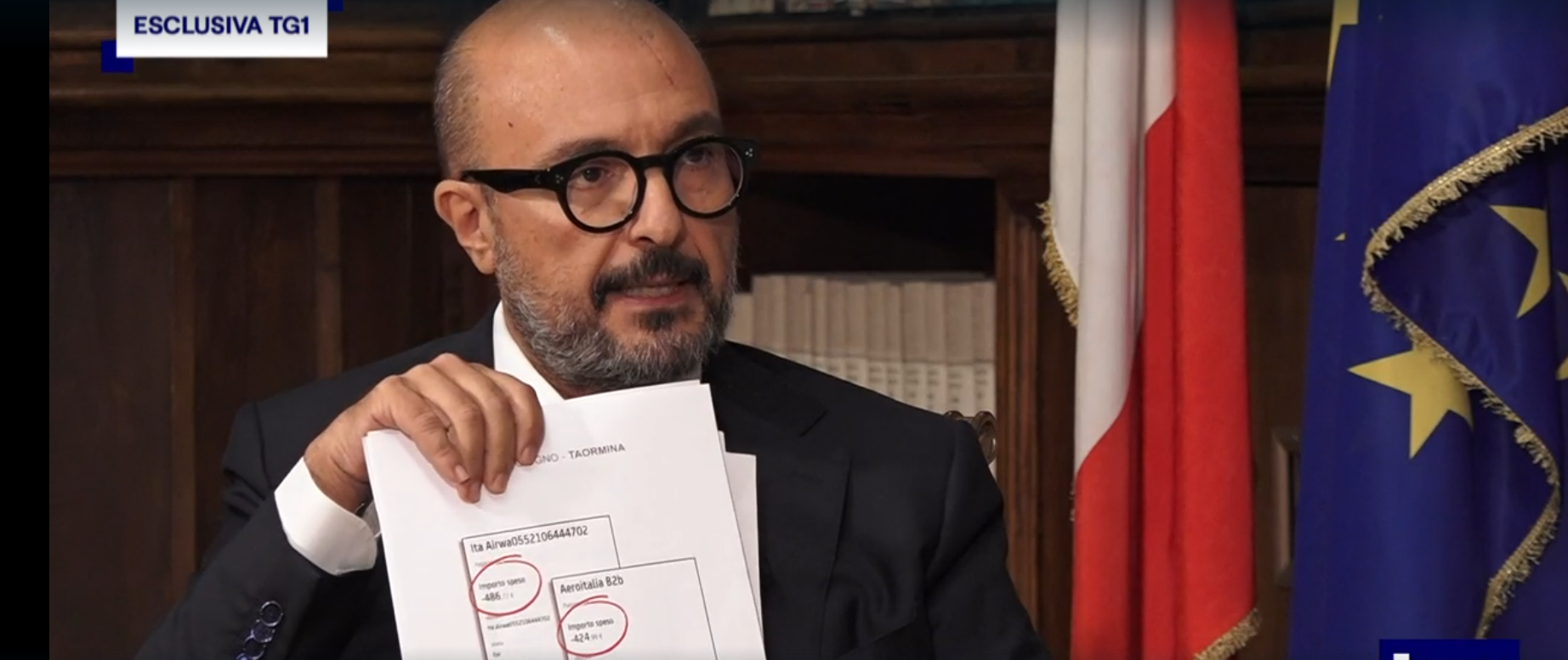 Gennaro Sangiuliano mostra lo stampato con le prenotazioni di biglietti aerei, durante l'intervista trasmessa dal tg1