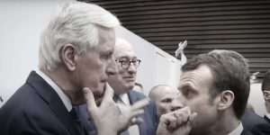 Barnier e Macron si guardano l'un altro (alle spalle si intravedono alcune persone)