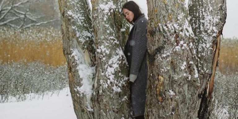 Una donna in piedi in mezzo a un gruppo di quattro alberi, in un paesaggio innevato. È la copertina del libro di Francesca Melandri che fa riflettere sulla guerra in Ucraina.