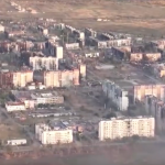 Una panoramica di Vuhledar, una delle prinicpali fortezze dell'Ucraina: si vedono gruppi di edifici colpiti da bombardamenti - semidistrutti, alcuni in parte bruciati. Nella parte in alto a sinistra dell'immagine una cortina di fumo si leva da un blocco di edifici