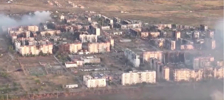 Una panoramica di Vuhledar, una delle prinicpali fortezze dell'Ucraina: si vedono gruppi di edifici colpiti da bombardamenti - semidistrutti, alcuni in parte bruciati. Nella parte in alto a sinistra dell'immagine una cortina di fumo si leva da un blocco di edifici