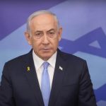 Il premier israeliano Netanyahu in un discorso pubblico. Accanto la bandiera di Israele