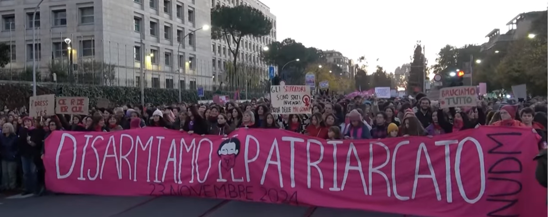 manifestazione non una di meno, una folla di manifestant* davanti allo striscione (rosa, con scritta bianca) "Disarmiamo il patriarcato"