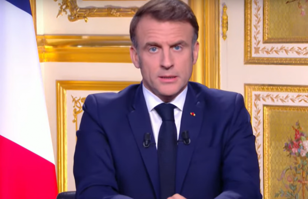 Emmanuel Macron dietro la scrivania presidenziale, alle sue spalle la bandiera della Francia