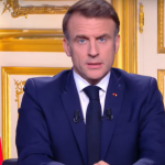 Emmanuel Macron dietro la scrivania presidenziale, alle sue spalle la bandiera della Francia