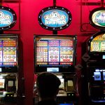 Un uomo di spalle guarda tre slot machine. La nuova legge di bilancio rischia di incentivare gioco d'azzardo e ludopatia.