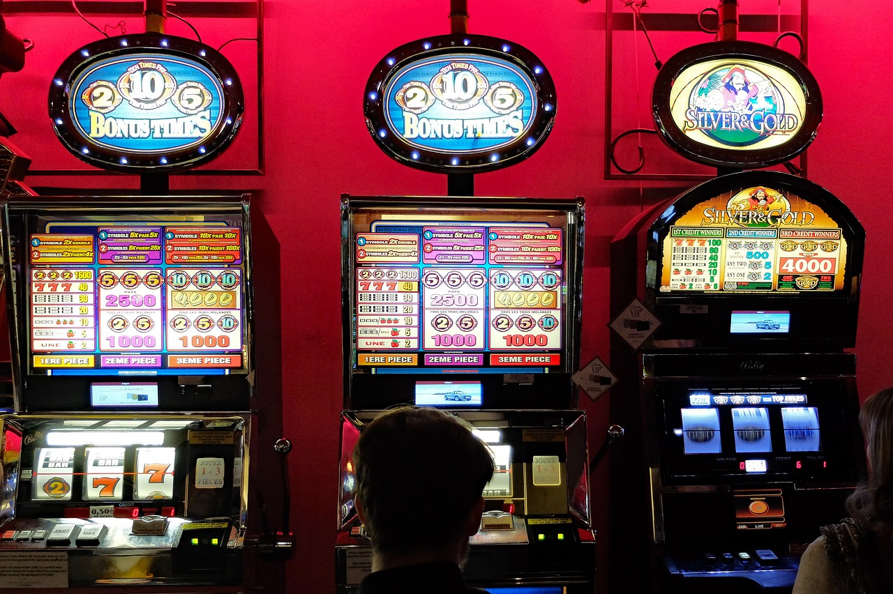 Un uomo di spalle guarda tre slot machine. La nuova legge di bilancio rischia di incentivare gioco d'azzardo e ludopatia.