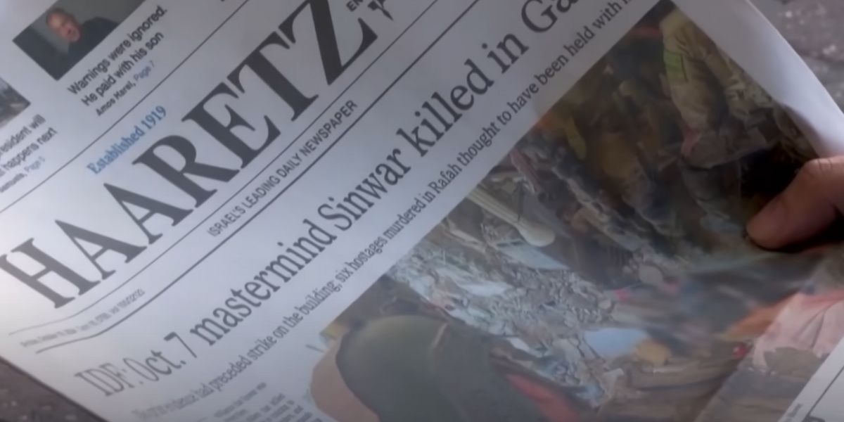 Una mano sfoglia il quotidiano israeliano Haaretz.