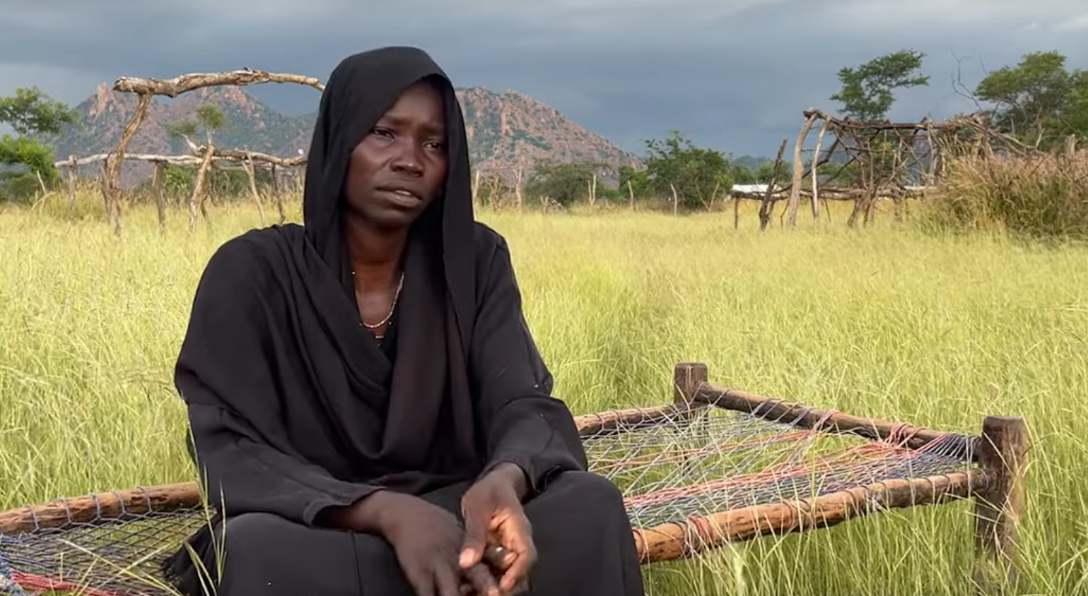 una donna sudanese seduta all'aperto mentre parla