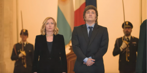 Javier Milei in posa con Giorgia Meloni (alla sua sinistra), dietro di loro due militari in divisa (un uomo e una donna) con la sciabola alzata