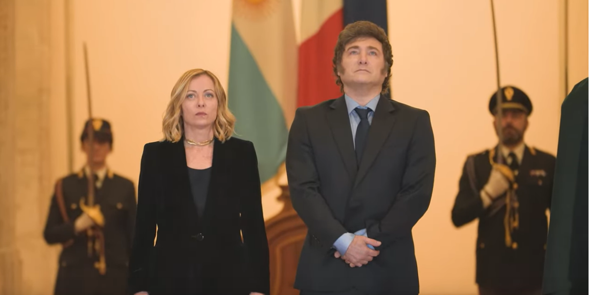 Javier Milei in posa con Giorgia Meloni (alla sua sinistra), dietro di loro due militari in divisa (un uomo e una donna) con la sciabola alzata