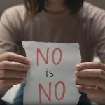 Una donna mostra un foglio con su scritto "No is No" per sensibilizzare sul concetto di consenso.