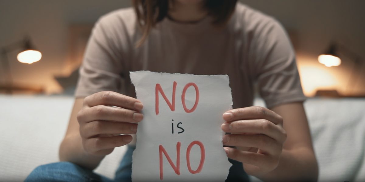 Una donna mostra un foglio con su scritto "No is No" per sensibilizzare sul concetto di consenso.