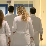 Un gruppo di 4 medici, di spalle, mentre cammina in un corridoio d'ospedale. La sanità italiana è in crisi.