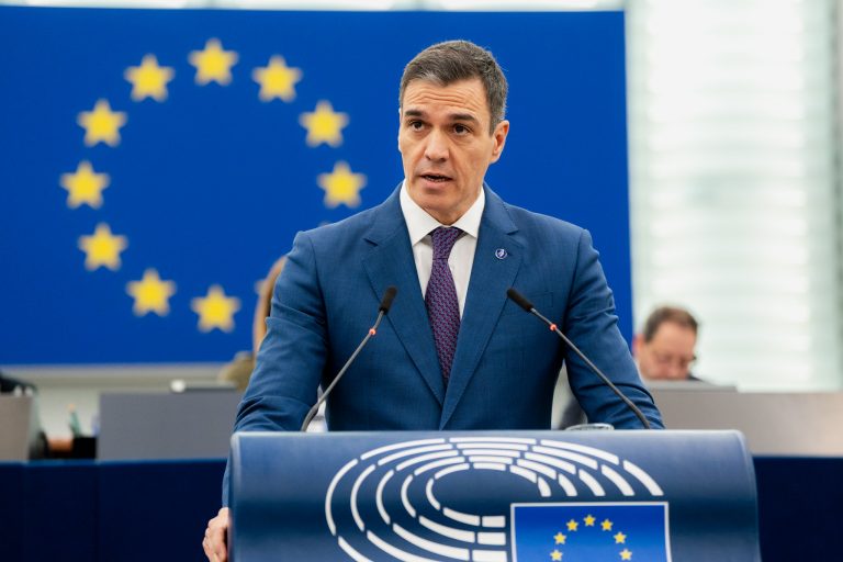 Il primo ministro della Spagna, Pedro Sánchez, durante un intervento al Parlamento Europeo. Sullo sfondo c'è una bandiera dell'Unione Europea.