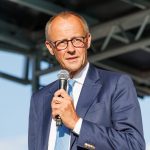 Friedrich Merz con il microfono in mano durante un comizio