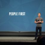 Mark Zuckerberg durante un evento pubblico, accanto a una scritta su sfondo azzurro che recita "People first"