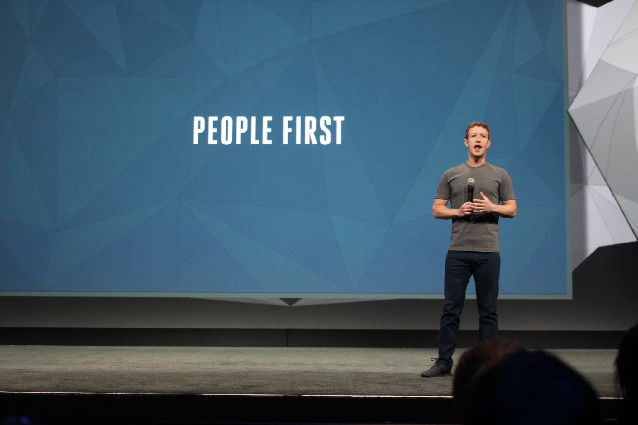 Mark Zuckerberg durante un evento pubblico, accanto a una scritta su sfondo azzurro che recita "People first"