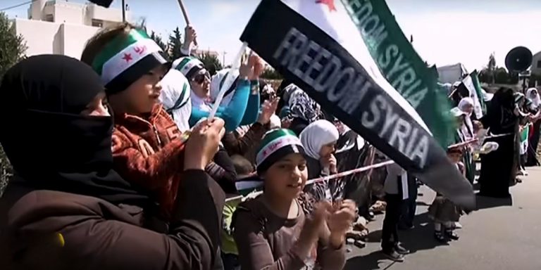 Folla di persone festeggia per la caduta del regime di Assad con striscioni con su scritto: "Freedom Siria"