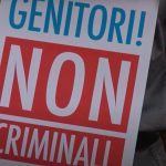 Un cartello con la scritta "Genitori! Non criminali." esposto da un manifestante contro la legge che punisce la GPA come reato universale