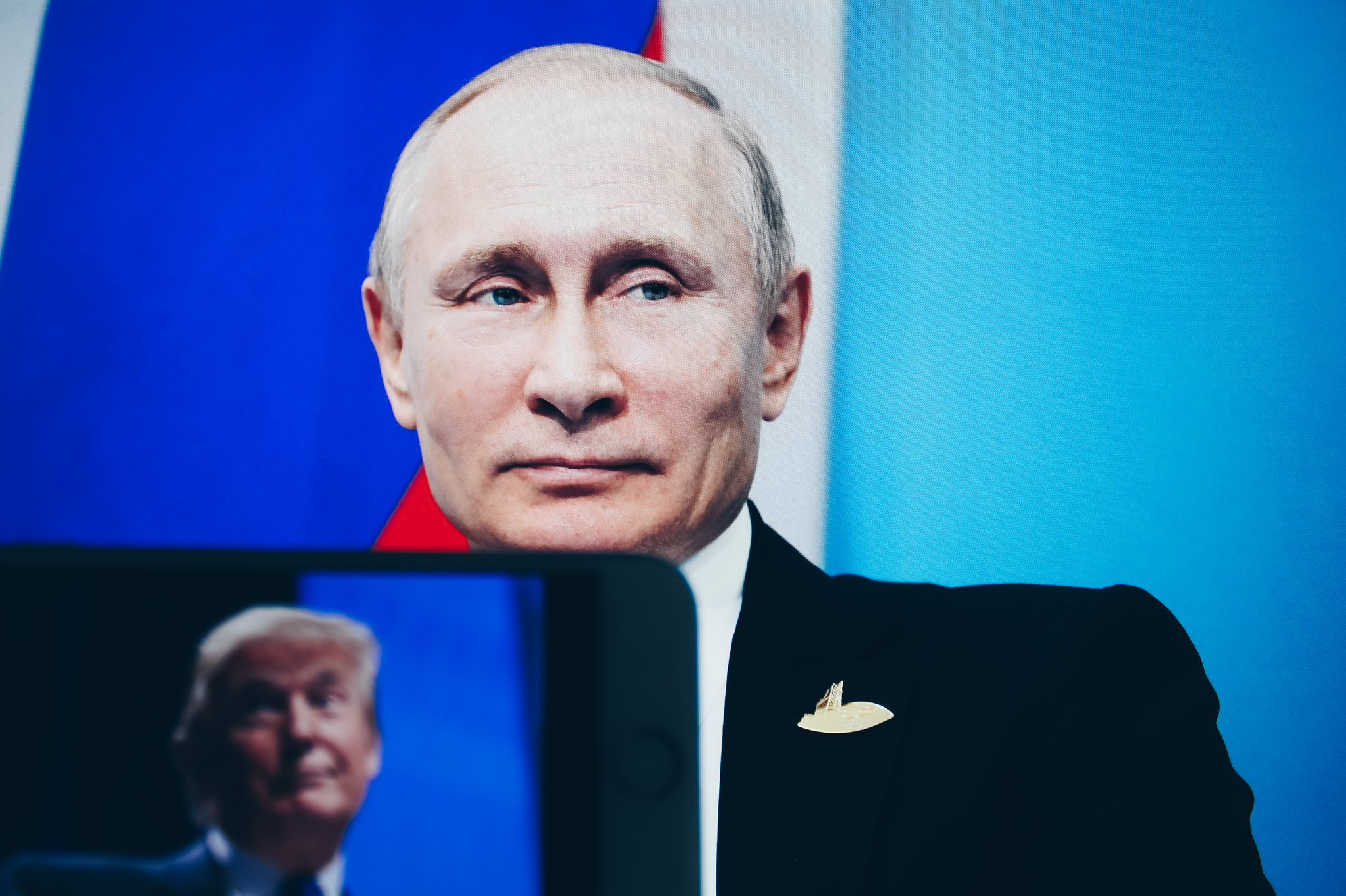 In primo piano il presidente della Russia Putin, davanti a lui un ipad dove si vede il volto del presidente USA Trump